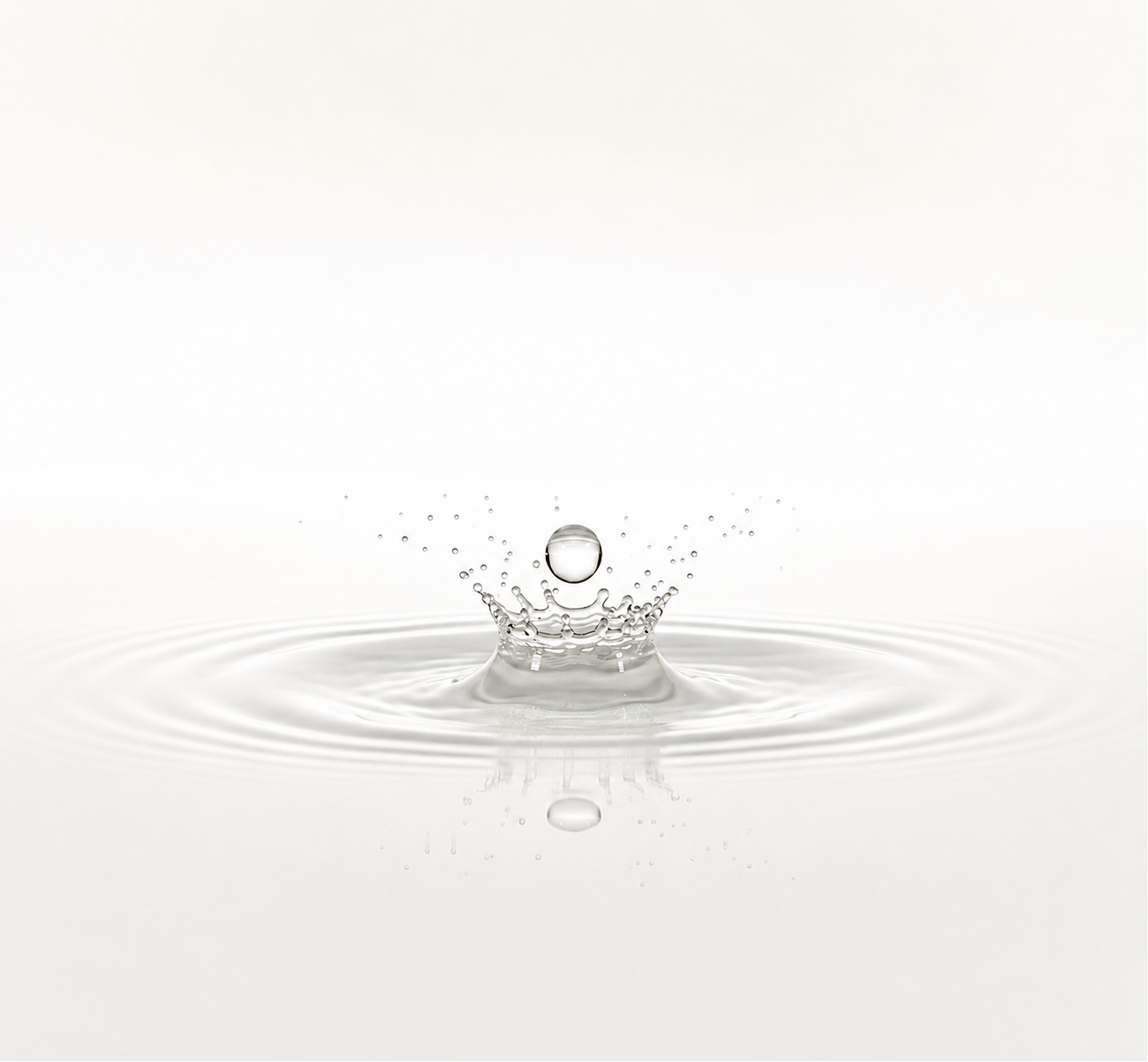 Water droplet creating ripples on a white background